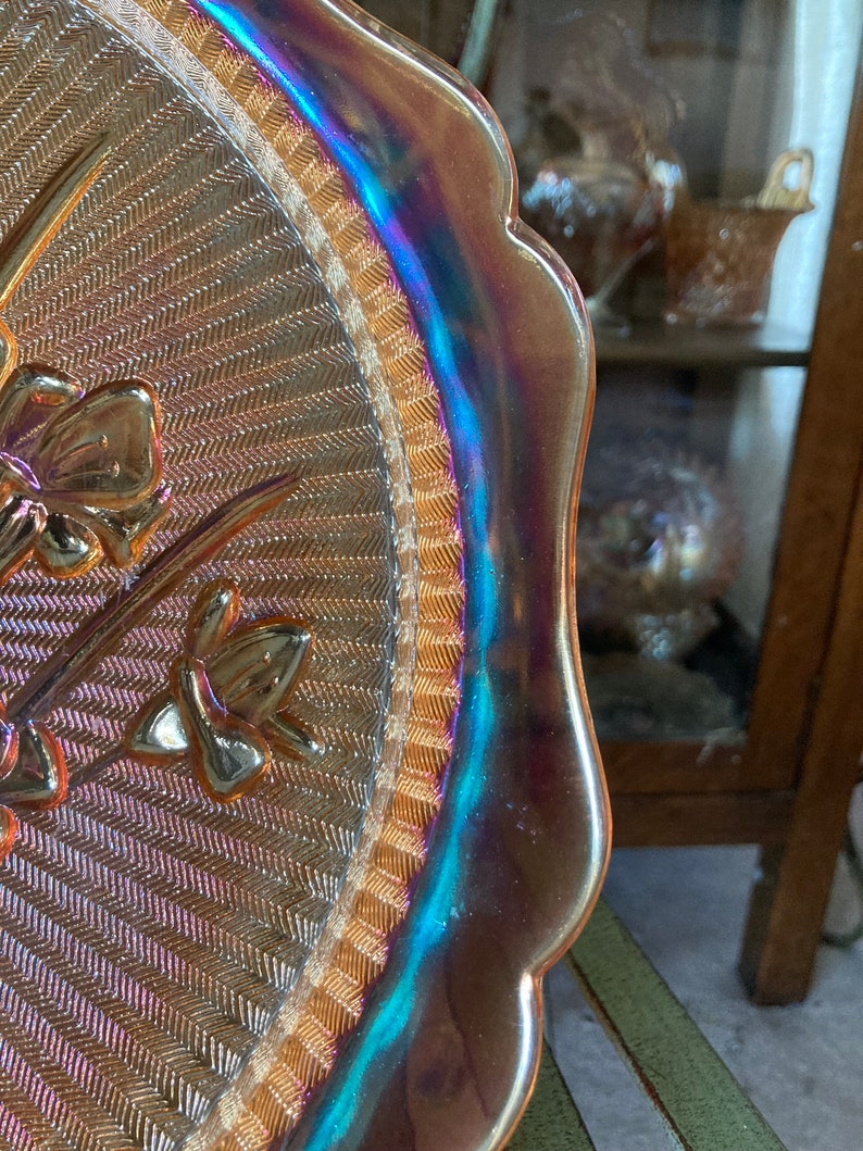 Peut inclure: Une assiette de service en verre iris&eacute; vintage avec un bord festonn&eacute; et un motif tiss&eacute;. L'assiette pr&eacute;sente un motif floral avec une bordure dor&eacute;e.