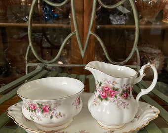 May include: A white porcelain sugar bowl and creamer set with a floral pattern. The set is on a white porcelain tray with a gold trim.