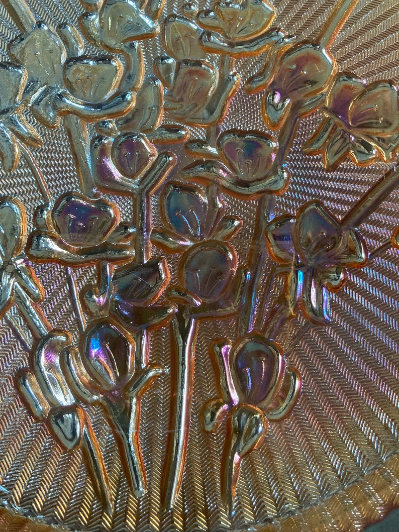 Peut inclure: Gros plan d'un plat en verre iridescent vintage avec un motif floral. Le plat a une surface textur&eacute;e et un bord festonn&eacute;.