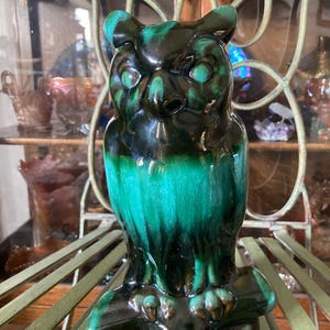 May include: A ceramic owl figurine with a black and green glaze. The owl is perched on a tree branch.