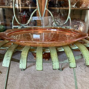 Peut inclure: Un plateau de service en verre vintage de couleur p&ecirc;che avec un motif d&eacute;coratif. Le plateau est pos&eacute; sur une chaise en m&eacute;tal vert.
