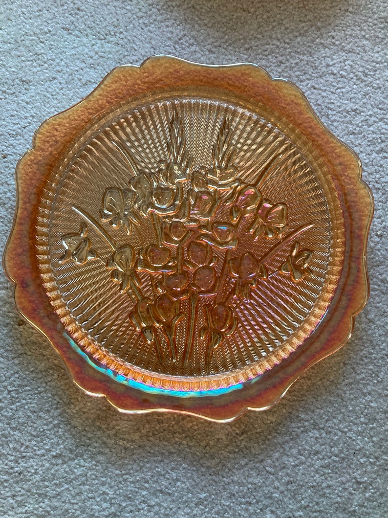 Peut inclure: Une assiette en verre ambr&eacute; vintage avec un bord festonn&eacute; et un motif floral. L'assiette a une surface textur&eacute;e et une finition iris&eacute;e.