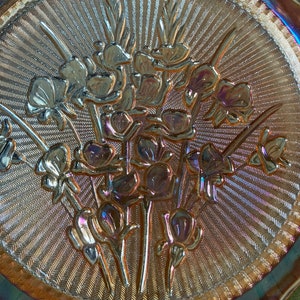 Peut inclure: Une assiette de service en verre iris&eacute; vintage avec un motif floral en relief. L'assiette a un bord festonn&eacute; et une surface textur&eacute;e.