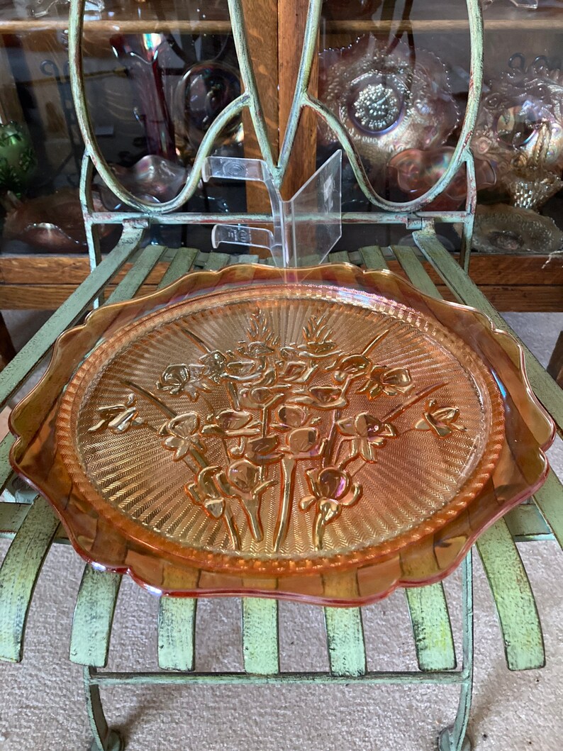 Peut inclure: Une grande assiette de service en verre ambr&eacute; avec un bord festonn&eacute;. L'assiette pr&eacute;sente un motif en relief d'un bouquet de fleurs.