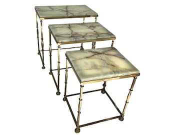 May include: Set of three nesting tables. Each table has a square, light green marble top with brown veining. The tables have a gold-colored metal frame with decorative accents and are arranged in a descending size.
