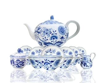May include: A blue and white porcelain tea set with a teapot, creamer, sugar bowl, and six cups and saucers. The set features a floral pattern with blue flowers and leaves on a white background.