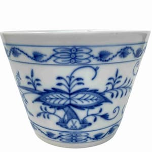 Op de afbeelding: Witte porseleinen beker met een blauw bloemmotief. De beker heeft een gedetailleerd ontwerp van bloemen en bladeren, met een rand van blauwe accenten. De beker heeft een licht uitlopende vorm en een gladde, glanzende afwerking.