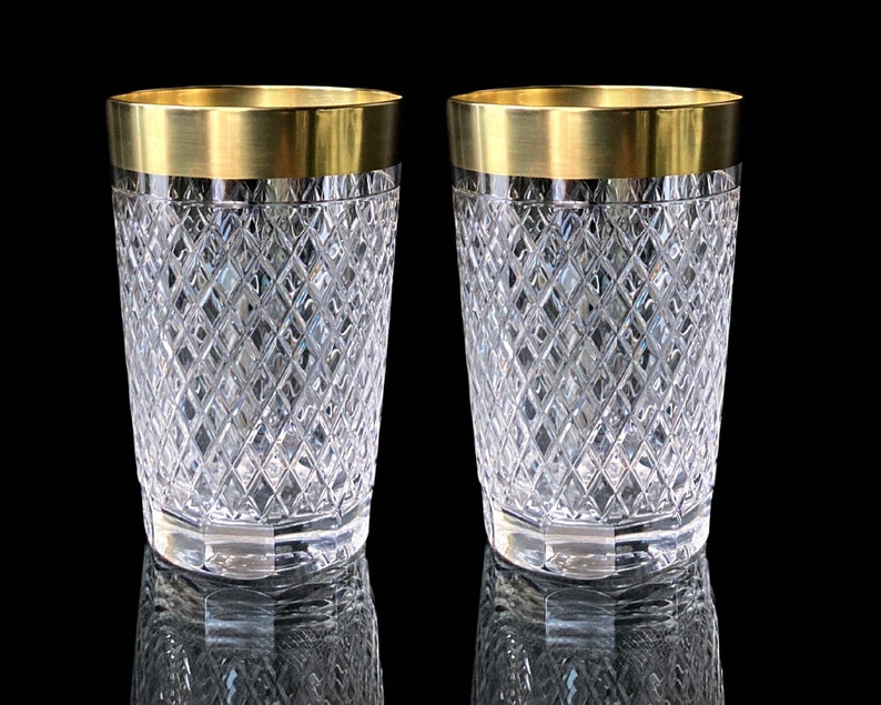 May include: Two clear glass tumblers with a gold rim. The glasses have a diamond pattern.