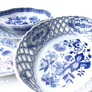 Op de afbeelding: Set van vier blauwe en witte porseleinen schalen met een bloemenpatroon. De schalen hebben een gegolfde rand en een delicaat tralieontwerp.