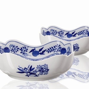 Op de afbeelding: Twee witte keramische kommen met een blauw en wit bloemenpatroon. De kommen zijn golvend gevormd en hebben een gegolfde rand.