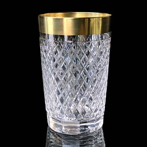 May include: A clear glass tumbler with a gold rim and a diamond pattern. The tumbler is on a black background.