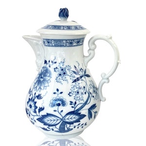 May include: A white porcelain coffee pot with a blue and white floral pattern. The pot has a lid and a handle.