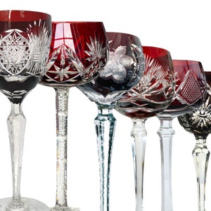 Op de afbeelding: Vijf wijnglazen met steel en ingewikkelde geslepen patronen. De glazen zijn allemaal rood en helder, met verschillende patronen.