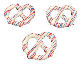 May include: Three white chocolate pretzels with red and blue stripes. The pretzels are arranged in a triangular pattern.