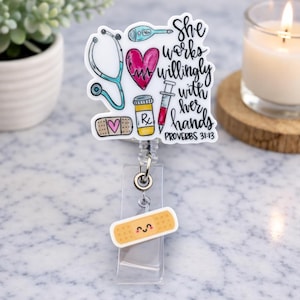 May include: A white badge reel with a medical theme. It features a stethoscope, heart, thermometer, pill bottle, syringe, and a bandage with a heart. The text reads "She works willingly with her hands" and "Proverbs 31:13".