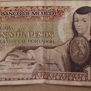 May include: A vintage 1000 Mexican pesos banknote. The bill features a portrait of a woman and text in Spanish. The note has a serial number and the text "El Banco de Mexico". The bill is primarily brown and tan.