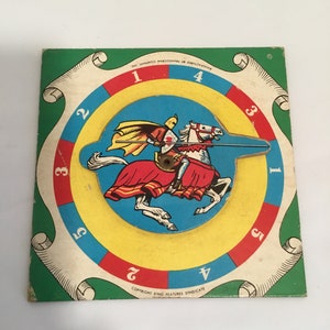 May include: A vintage game board with a spinning wheel featuring a knight on horseback. The wheel has numbers 1 through 5 on it. The board is green with a white scroll design and the text "COPYRIGHT KING FEATURES SYNDICATE" and "MANUFACTURED BY TRANNOS COMPANY INC".