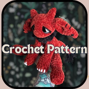 May include: A red crocheted creature with black accents, white claws, and large black eyes. The plush toy has a ruffled black collar and pointed ears. The words "Crochet Pattern" are displayed across the bottom of the image.