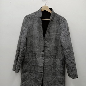 May include: A grey and black checked blazer with a single-button fastening. The blazer features long sleeves and a black interior lining. It is suspended on a wooden hanger against a white backdrop.
