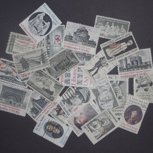 May include: A collection of vintage postage stamps featuring various designs, including architecture, historical figures, and events. The stamps are in various colors and sizes, and some have text such as "Architecture USA 5c" and "John Paul Jones 1747-1792".