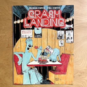 May include: A comic book cover with a red and white neon sign that reads "Crash Landing". The cover features two blue cartoon characters sitting at a table in a diner. The text "World Famous Corndogs" and "I Want to Believe" are visible on the wall behind the characters. The text "Lincle Sam Wants You" is visible on the wall to the right of the characters.