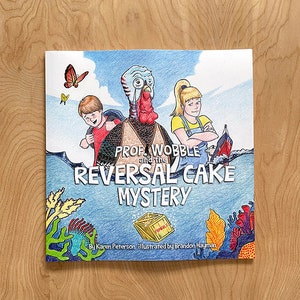 Könnte beinhalten: Eine Buchcover-Illustration mit einem Truthahn, der eine Brille und einen Rucksack trägt, einem Jungen und einem Mädchen sowie einer Kiste mit der Aufschrift "Fragile". Der Titel des Buches lautet "Prof. Wobble und das Geheimnis des umgekehrten Kuchens".