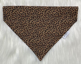 May include: A brown and tan leopard print bandana with a white tag that says "Jimbo's Originals".