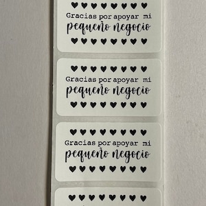 May include: Four white rectangular stickers with black text and hearts. The text on the stickers reads "Gracias por apoyar mi pequeño negocio".