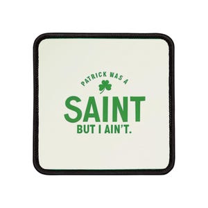 May include: Square coaster with a white background and a black border. The coaster features the text "PATRICK WAS A SAINT" above the word "SAINT" in green, with a green shamrock. Below, it reads "BUT I AIN'T."