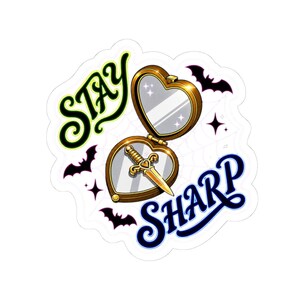 May include: A sticker featuring a heart-shaped compact mirror with a gold frame and a dagger inside. The text "STAY SHARP" is written in green and blue, with bat and star illustrations.