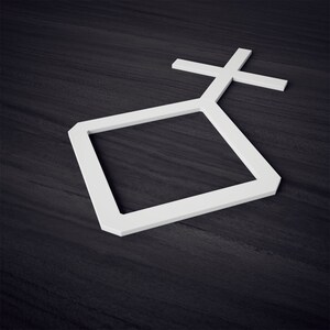 K&ouml;nnte beinhalten: Eine wei&szlig;e geometrische Form mit einem Quadrat und einem Kreuz auf einem dunklen Holzgrund.