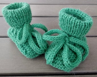 May include: A pair of green knitted baby booties with a tied bow.