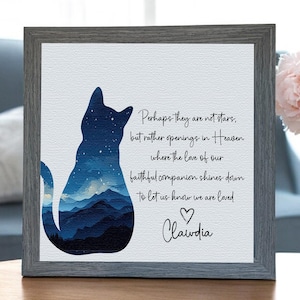 May include: A framed print with a cat silhouette design filled with a blue mountain scene. The print includes the text "Perhaps they are not stars..." and the name "Clawdia" below a heart symbol. The frame is grey.