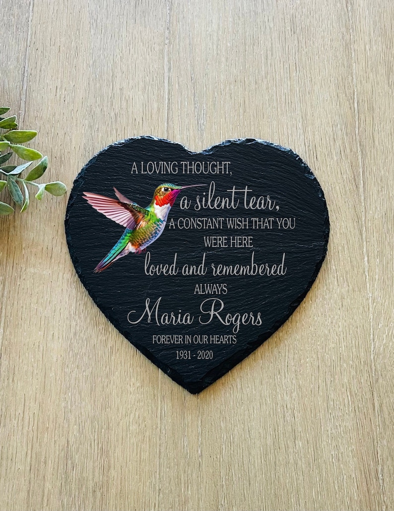 May include: Black heart-shaped slate with a hummingbird image and the text "A loving thought, a silent tear, A constant wish that you were here loved and remembered always Maria Rogers Forever in our hearts 1931-2020".