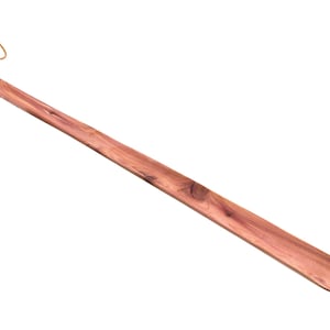 May include: A wooden shoe horn with a brown leather loop at the top. The horn is made of light brown wood with a natural grain.