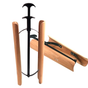 May include: Two boot trees featuring curved light brown wooden panels connected by a black metal frame. Each device includes a vertical black handle at the top and a tension mechanism designed to expand the wooden sections to maintain boot shape.