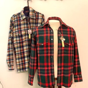 Puede incluir: Dos camisas de franela a cuadros, una colgando y otra en un maniqu&iacute;. La camisa colgante tiene un patr&oacute;n azul, rojo, amarillo y blanco. La camisa del maniqu&iacute; es roja y verde. Ambas camisas tienen cuello y cierre de botones.