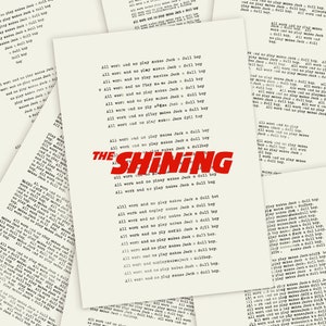 Peut inclure: Une affiche rouge et blanche avec le titre "The Shining" en lettres rouges gras. L'affiche présente le texte "All work and no play makes Jack a dull boy" répété plusieurs fois en blanc.