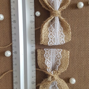 Peut inclure: Deux n&oelig;uds en toile de jute avec une garniture en dentelle blanche. Les n&oelig;uds sont attach&eacute;s avec de la ficelle et mesurent environ 10 cm de long.