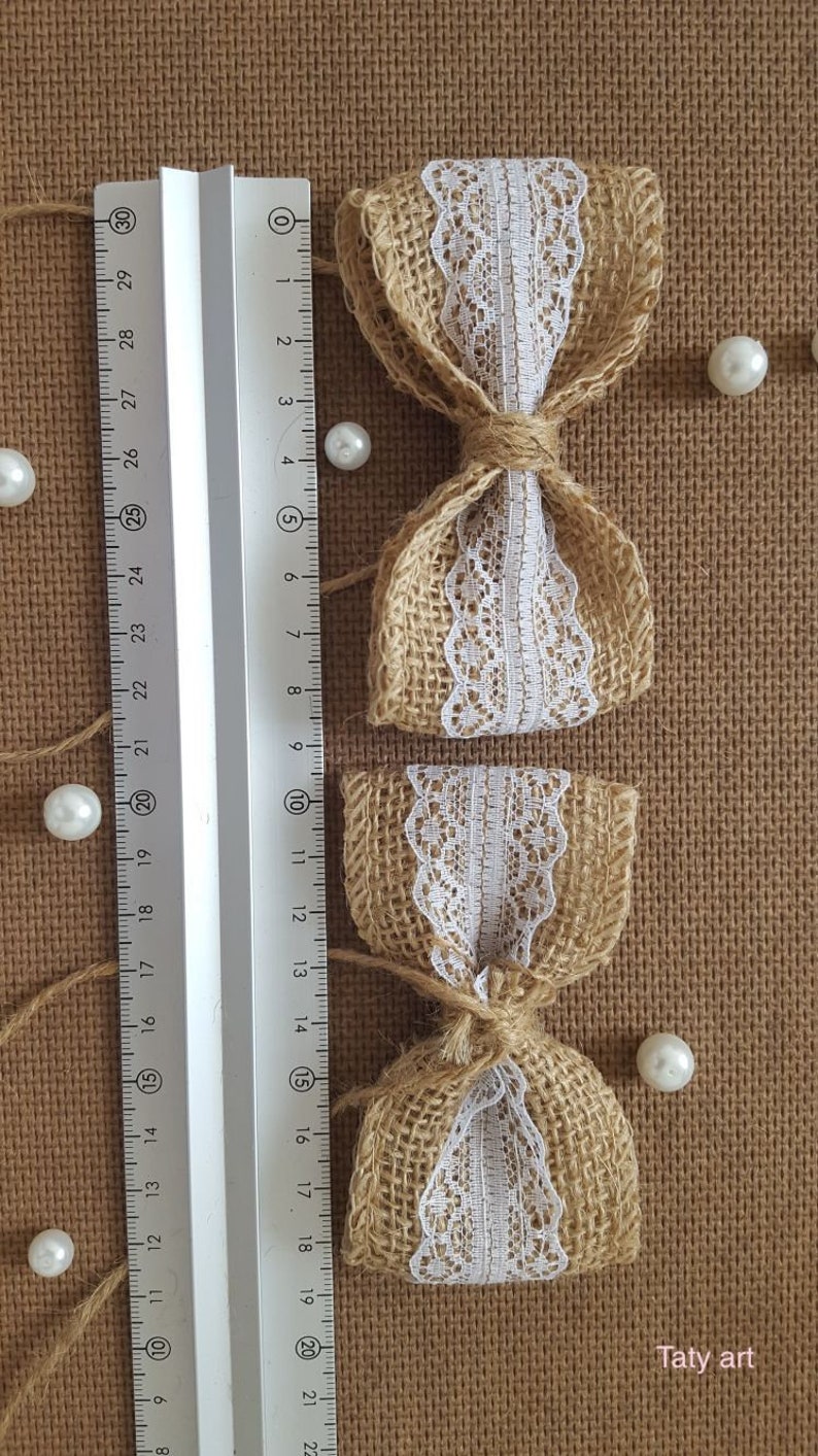 Peut inclure: Deux n&oelig;uds en toile de jute avec une garniture en dentelle blanche. Les n&oelig;uds sont attach&eacute;s avec de la ficelle et mesurent environ 10 cm de long.