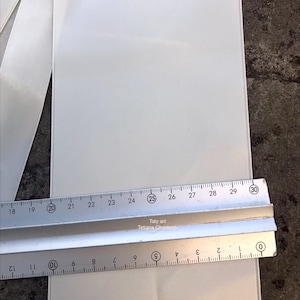 Op de afbeelding: Een close-up van een witte stof met een liniaal die de lengte meet. De liniaal toont metingen van 0 tot 30 cm, met de tekst "Taty art Tetiana Chankrob" zichtbaar. De stof lijkt een licht, getextureerd materiaal te zijn.