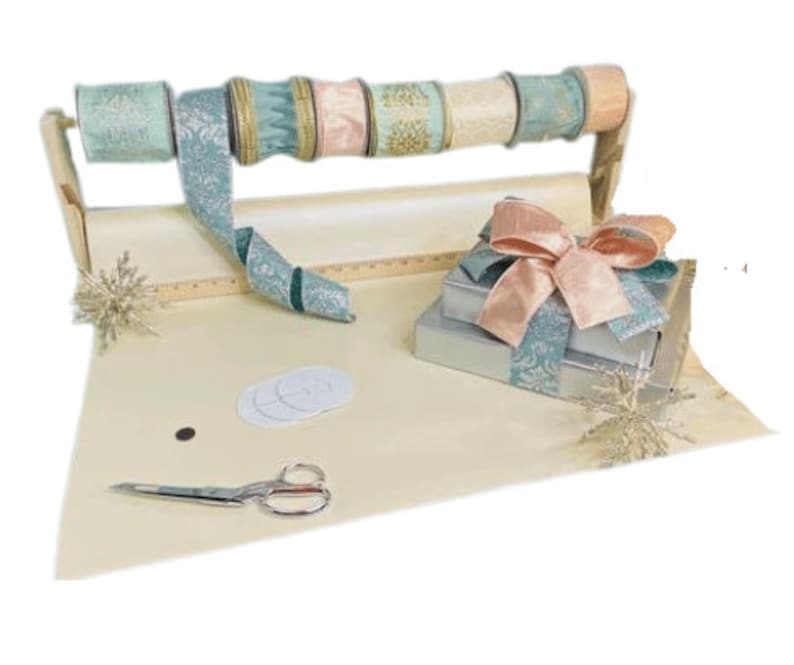 Puede incluir: Un conjunto de papel de regalo, cinta y cajas de regalo en una gama de colores azul claro y rosa. El papel de regalo es beige y la cinta es azul verdoso con un patr&oacute;n blanco. Las cajas de regalo est&aacute;n envueltas en papel azul verdoso con un patr&oacute;n blanco y coronadas con un lazo de sat&eacute;n rosa.