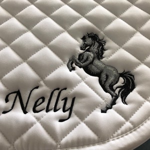 May include: White quilted saddle pad with black embroidery of a horse and the name "Nelly".
