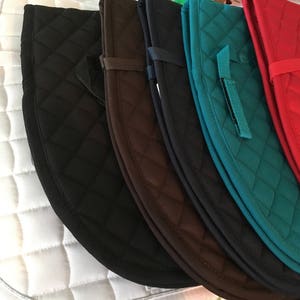 May include: A set of six quilted saddle pads in various colours, including white, black, brown, teal, navy, and red. The pads are made of a soft, quilted material and have a diamond pattern.