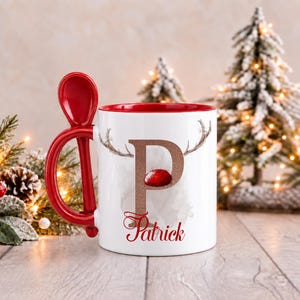 May include: A white ceramic mug with a red interior and a matching red spoon integrated into the handle. The front features a large letter P in a glittery copper finish, topped with reindeer antlers and a red nose, with the name Patrick below.