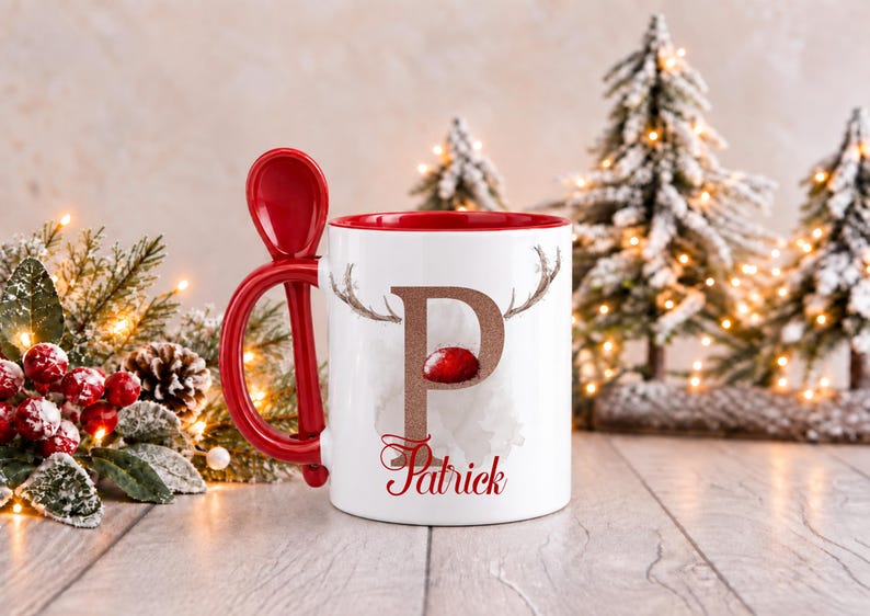May include: A white ceramic mug with a red interior and a matching red spoon integrated into the handle. The front features a large letter P in a glittery copper finish, topped with reindeer antlers and a red nose, with the name Patrick below.