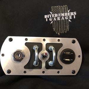 May include: A silver metal panel with a key ignition, a toggle switch, and a dual USB port. The panel is labeled "Dive Bombers Garage" with an American flag graphic.
