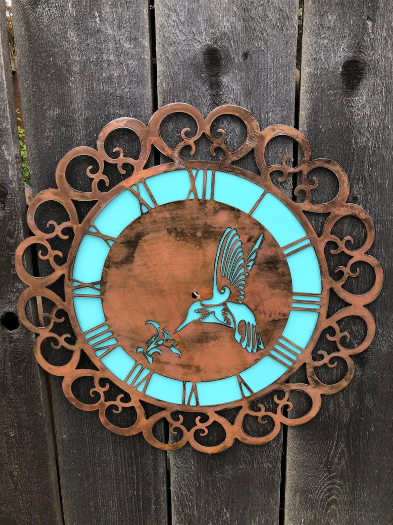 May include: A copper-colored metal clock with a turquoise blue face and a hummingbird design. The clock has a decorative, ornate frame.