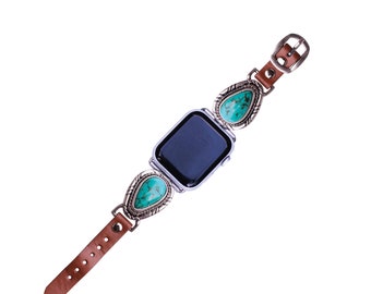 May include: A brown leather watch band with turquoise stones and silver accents. The watch face is black and the band has a buckle closure.