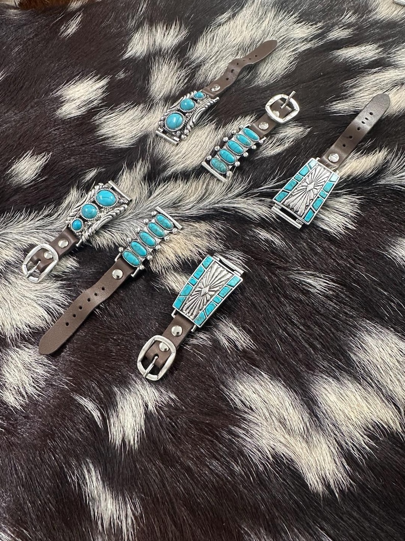 May include: Five different watch bands with turquoise stones and silver accents. The bands are made of brown leather and have a buckle closure.